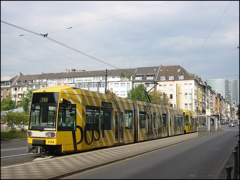 Straenbahn-Haltestelle Kirchplatz in Dsseldorf am 23.09.2006. Ein Zug der Linie 703 mit zwei Niederflur-Triebwagen hat gerade gehalten. Beide Triebwagen tragen die gleiche auffllige Werbung fr eine der groen Tageszeitungen der Region.