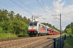 186 498 von DB Cargo Nederland zieht einen langen mit Land Rover beladenen Autozug durch den Gemmenicher Wald bei Moresnet-Chapelle in Richtung Visé. Aufnahme vom 19.06.2019.