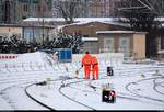 Blick auf zwei Bahnmitarbeiter, die versuchen, die Weichen des Gleisvorfelds von Halle(Saale)Hbf von Schnee und Eis zu befreien.