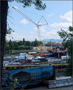 Ein Blick über die Brückenbaustelle -    Während vorne ein Stadtbahn der Linie U14 vorbeifährt, fährt jenseits der Baustelle für die neue Neckarbrücke gerade ein