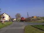 212 084 am 18.04.2008 mit einem Gterzug bei der berquerung eines B in Schlsselfeld.