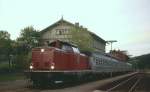 212 327-1 steht an einem Maiabend 1980 mit einem Nahverkehrszug abfahrbereit im Bahnhof Bayerisch Eisenstein, die mitten durch den Bahnhof verlaufende deutsch-tschechische Grenze ist im Hintergrund