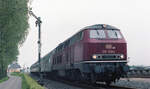 DB 215 032-4 mit E-3778 (Siegen - Nijmegen) bei der Abfahrt vom Gleis 1 in Kranenburg am 15.05.1983. Der Zug passiert gerade Formsignal  H , das noch Propangasleuchten hat. Scanbild 93075, Kodacolor400.