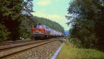 Mit einem Güterzug ist 218 209-5 im Juli 1985 bei Velden im Pegnitztal unterwegs
