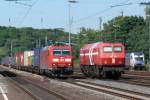 Zugbegegnung in Köln-West. 185 018 mit einem Güterzug am Haken kreuzt die DE13 der HGK. Rechts halb verdeckt parkt die ES64U2-077 der Wiener Lokalbahnen. Aufgenommen am 13/06/2009.