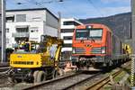 Bahnbau in Vorarlberg: Die ÖBB nutzen die Streckensperre im Zuge der Bauarbeiten zwischen Lauterach und Hard, um gleichzeitig auch im Bahnhof Bregenz die nicht mehr zeitgemäßen Holzschwellen durch Betonschwellen zu ersetzen (als erster Schritt in Richtung Bahnhofsneubau). Obwohl die Rail Transport Service GmbH (RTS) ein österreichisches Unternehmen ist (es steht auch die Grazer Adresse auf der Lok), wurde die Diesel-Vectron 247 902 in Deutschland registriert (92 80 1247 902-0 D-RTS). Neben der Lok steht am 09.04.2021 ein Liebherr-Zweiwegebagger der Bahnbau Wels an der West-Einfahrt in den Bahnhof Bregenz. Fotostandort: am öffentlichen Weg, über den Zaun fotografiert.