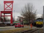 DE676 der ASCENDOS fhrt mit den leeren Kesselwagen am 08.03.2012 ber einen unbeschrankten und nicht mit Lichtzeichen ausgestatteten Bahnbergang, der von einem Bahnmitarbeiter gesichert wird.