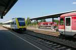 Blick zwischen einem schnell durchfahrenden und einem stehenden Zug auf den Mittelbahnsteig und einen abgestellten Triebwagen der Baureihe 650 im Bahnhof von Aulendorf.