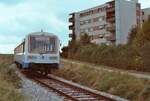 Der Zug der Strohgäubahn Korntal-Weissach und das Hochhaus daneben entsprechen sich in etwa in ihrer Farbgebung. Wagen der Baureihe NE 81 wie hier auf der Strohgäubahn wurden nur an Nichtbundeseigene Eisenbahnen geliefert. Erstauslieferung war 1981, also ist hier ein Wagen der ersten Serie vorhanden, das Foto ist von 1983