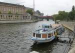 Ein Regionalexpress fährt über die Spree und davor wartert ein Tour-Schiff auf seine Passagiere.