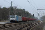 Im Schneeregen wartet die 186 271-3 der Railpool mit einem Holzzug am 03.02.2018 im Bahnhof Nassenheide..