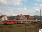 Im Bahnhof von Kronach wartet Baureihe 111 220-0 mit einen Regionalzug. Das graue Gebude in Bildmitte ist das Empfangsgebude. Das grne rechts daneben das Gebude der Deutschen Post.