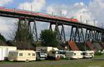 Nochmal Rendsburg von mir: Eine 143 mit SH-Express befährt die eiserne Brücke. Unten die Wohnsiedlung und auf dem Platz bei der Halle die Vorboten oder Nachwehen eines Volksfestes etc... Foto vom 26.08.2012.