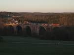 Schatten des Hügels streift die Elstertalbrücke mit dem Autozug nach Nürnberg und der 155 083.