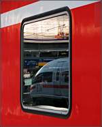 Fern im Nah -     München Hauptbahnhof: Im Fenster eines Doppelstockwagens spiegelt sich ein ICE 3.