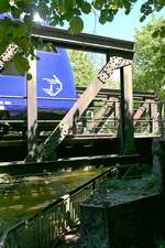 Zwischen den Trägern einer noch aus den Anfangsjahren der Südbahn stammenden Brücke über die Schussen das Logo der Bodensee-Oberschwaben-Bahn, der Geißbockkopf, eines von Aulendorf nach Friedrichshafen Hafen fahrenden Triebwagens. 02.06.2019 Nähe Aulendorf.