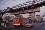 Nahe dem Bahnhof Zoo in Wuppertal überquert am 7.12.1989 ein Gliederzug der Wuppertaler Schwebebahn die Talstraße.
