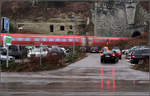 Oben hui, unten pfui -

... könnte man sagen. Neben dem Tunnelportal des Überlinger West-Tunnels befindet sich eine Felswand mit höhlenartigen Öffnungen. Darunter 'verschandelt' der Parkplatz für die Überlinger Therme das Motiv. Während ein Zug meist harmonisch in seinem Umfeld wirkt, stören Autos doch eher sehr. 
Der IRE befindet sich auf der Fahrt nach Ulm fährt in den Tunnel ein und wird am anderen Ende in Überlingen anhalten.

Die Geschichte zum Bild:
Eigentlich hatte ich während dieses Spazierganges nicht vor an diesem Portal zu fotografieren. Doch kamen wir zufällig zu einem passenden Zeitpunkt hier vorbei. Nach ein paar Bildern mit dem Regionshuttle aus anderer Perspektive wollte ich doch mal versuchen, diese Felswand mit dem IRE ins Bild zu bekommen. Mein erster Standpunkt war hinter den Autos direkt an der Strecke. Auch da war der Plan mit Bewegungsunschärfe zu arbeiten. Da aber ein Schneeschauer einsetzte suchte ich kurzerhand nach einer Unterstellmöglichkeit, die in Form eines Bus-Wartehäuschen auch zu finden war. Dann war es noch spannend ob zum Zeitpunkt der Zugdurchfahrt Fußgänger oder ein LKW bzw. Bus die Bahn verdecken würden, was dann zum Glück nicht der Fall war. Ein zufälliges Plus ist dann noch die Spiegelung der roten Rücklichter auf dem regennassen Asphalt, der einen vertikalen Kontrapunkt zum horizontalen roten Streifen des Zuges setzt...

11.02.2017 (M)

