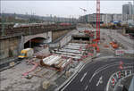 Wenn der Tunnel aus der Oberfläche ragt - 

... muss die querende Fahrbahnen in großen Schlaufen drum herum geführt werden um dann unter den Brücken durchzukommen. Wenn dann später die Bahnbrücken überflüssig werden, wird das Gelände hier höher liegen und die Straßen wieder direkt geführt werden können.

Die S-Bahnen fahren auf sechs Linien tagsüber im 15 Minuten-Takt, das heißt im Durchschnitt wird alle 1,25 Minuten eine Bahn durch den Tunnel fahren, beide Richtungen gerechnet. Würde man an so einer stark befahren Strecke einen beschrankten Bahnübergang anlegen, wäre diese praktisch immer geschlossen.

Dieser Abschnitt und der Anschluss an den bestehenden Tunnel sind die einzigen Stellen der S-Bahntunnel-Verlängerung, wo noch die Rohbauarbeiten im Gange sind.

01.02.2022 (M)
