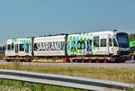 Saarbahntriebwagen auf einem Schwerlastanhänger, abgestellt auf einem Abstellplatz an der A 61 bei Meckenheim.