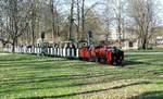 Dresden, 07.04.18 Nach dem Trubel beim Dampfloktreffen darf es dann auch mal etwas ruhiger und überschaubarer sein,da bietet sich die 381-mm-Spur der Dresdener Parkbahn im Großen Garten förmlich an. Während die meisten Gäste ihre Zeit auf den üblichen Touristenpfaden verbringen, klinkt sich der  Kenner  eben mal aus.
An diesem Tag war ( erwartungsgemäß fast ) alles in Bewegung, was spurweitenmäßig auf die schmalen Gleise passte,etwa 10-Minuten -Takt an zweigleisger Strecke, da kommt keine Langeweile auf! Wetter herrlich, die Dresdener frequentieren ihren  Großen Garten inclusive Parkbahn,Zoo und anderen Events  schon aus Gewohnheit gern.
Hier nähert sich Lok  Moritz  Baujahr 1925 Krauss/München 8353  als Verkleinerung 1:3,33 mit volbesetzten Zug dem Fotografen.Grad hat man den neugebauten Bahnhof Gläserne Manufaktur  am Straßberger Platz verlassen und strebt eilig auf zweigleisigem Abschnitt dem Bahnhof  Zoo  entgegen.
Enstanden ist die Bahn als Geschenk an die damaligen Kinder und Erwachsenen Dresdens nach Kriegsende, eine einfache Streckenführung ermöglichte in damaliger Zeit Entspannung vom Alltag in der zerstörten Stadt.Am 01.Mai 1951 erfolgte dann die Eröffnung als Pioniereisenbahn mit neuer Streckenführung, bei der Kinder und Jugendliche alle Funktionen des Bahnbetriebes übernahmen, altergemäß gestaffelt. Nur Lokpersonal und Leitung lagen in Erwachsenen(Eisenbahner)Hand.
Der zweigleisige Abschitt diente dazu, das Betriebsgeschen auf solchen Strecken authentisch nachstellen zu können, sollten doch möglichst viel Pioniere ihre Laufbahn bei der DR fortsetzen.Selbst Falschfahrbetrieb konnte hier durchgeführt werden, man beachte die Signale!  