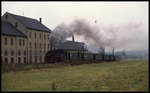 Am Stadtrand von Zittau dampft hier am 7.10.1992 die 99725 mit ihrem Personenzug Richtung Bertsdorf an einem alten Fabrikgebäude vorbei.