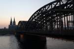 Abendstimmung am 13.03.2014 in Köln. Kurz nachdem die Sonne an diesem wunderschönen Tag über der heimlichen nordrhein-westfälischen Hauptstadt untergegangen ist, schleicht ein ICE über die Hohenzollernbrücke gen Hauptbahnhof, während die Türme des Doms, fast wie zwei Messer, in den sich verdunkelnden Himmel ragen.
