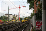 . Von der Straßenbahn zur Stadtschnellbahn -

Südlich des Bahnhofes von Stuttgart-Feuerbach hat sich das Bild sehr gewandelt im Vergleich zu den Aufnahmen von Horst und Kurt:

http://www.bahnbilder.de/bild/deutschland~strassenbahn~stuttgart-keine-stadtbahn/896341/einzige-abwechslung-im-stuttgarter-gt4-einerlei-waren.html

http://www.bahnbilder.de/bild/deutschland~strassenbahn~stuttgart-keine-stadtbahn/689684/stuttgart-ssb-sl-13-gt4-747.html

Die Bahn fährt jetzt auf unabhängiger Trasse wofür die Bahngleise überdeckelt wurde. Weiter oben in Richtung Pragsattel geht es in einen Tunnel. Das Backsteingebäude rechts ist noch vorhanden, das andere Gebäude war der Stadtbahntrasse im Weg. Ein Fertigteilbetonmauer trennt die Bebauung recht unsensibel von den Gleisen.

23.07.2016 (M)