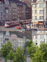 Ein Blick von der S-Bahn-Station Düsseldorf-Oberbilk auf die Kreuzung Siegburger Straße/Oberbilker Allee: Oben verlässt ein GT8SU-Doppel die oberirdische Haltestelle Siegburger Straße im Frühjahr 2002, rechts neben dem hinteren Fahrzeug ist einer der damals bereits fertiggestellten Zugänge zur Tunnelstation zu erkennen. Auf der unteren Aufnahme vom 06.06.2023 zeigt sich das Umfeld wesentlich grüner und auch die Gebäude haben inzwischen eine optische Auffrischung erhalten.