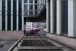 Durchblick -    Blick unter einem Neubau hindurch auf einen U-Bahnzug der Hamburger Linie U3, der von der Station Rödingsmarkt hinunter zur Haltestelle Rathaus rollt.