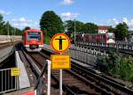 Vom S-Bahnsteig der Hamburger Station  Barmbek  geht der Blick auf einen ausfahrenden Zug der Linie S1 und auf einen abgestellten DT3-Zug der Hochbahn.