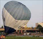 Ballonstart und Straßenbahn -     Während auf der Wiese an der Elbe ein Ballon sich zu seiner Fahrt aufrichtet, quert dahinter auf der Carolabrücke ein Straßenbahn die Elbe.