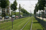 Die Straßenbahn in Freiburg-Rieselfeld -

Am 13. September 1997 wurde die Straßenbahn in den neuen Stadtteil Rieselfeld eröffnet. Zunächst wurde das Rieselfeld über die Strecke durch Weingarten angefahren mit einem Abzweig an der Haltestelle 'Lindenwäldle,' Die heutige Strecke von der Innenstadt über Wiehre und Haslach ging in den Jahren 2004 und 2002 in Betrieb. Seither verkehren die Bahnen ins Rieselfeld über diese Strecke.

Hier ein Blick von der ersten der drei neuen Haltestellen 'Geschwister-Scholl-Platz' auf den abgezäunten Rasenbahnkörper in Richtung der Umsteigehaltestelle 'Lindenwäldle.'

11.05.2006 (M)