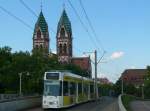 Wagen 245 auf der Linie 5 nach Rieselfeld, im Hintergrund die Herz-Jesu-Kirche.