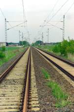 Der Abschnitt Gterglck–Wiesenburg (Mark) der legendren  Kanonenbahn  wurde 1992 zweigleisig ausgebaut, 1993 elektrifiziert und anschlieend u.a. vom Fernverkehr Rheinland/Ruhrgebiet–Hannover–Berlin genutzt. Nach Abschluss der Elektrifizierung Magdeburg–Brandenburg–Berlin (1995) und Inbetriebnahme der Schnellfahrstrecke (Hannover–)Oebisfelde–Berlin (1998) verblieb hier nur noch bescheidener Nah- und Gterverkehr. Ende 2004 erfolgte die Stilllegung dieser zweigleisigen elektrifizierten Hauptbahn. Das Foto entstand am 20.05.2005 auf einem Bahnbergang zwischen Lindau (Anhalt) und Deetz.