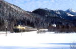 Winter im Bayerischen Oberland: An einem traumhaften Wintertag Anfang Januar 1991 ist eine 218 mit einem Zug von Bayrischzell nach München kurz vor Fischbachau unterwegs, im Hintergrund der 1.838