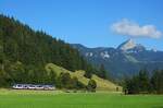 Ein LINT 54 der Bayerischen Regiobahn ist am 04.09.2023 bei Aurach in Richtung München unterwegs, im Hintergrund der 1838 m hohe Wendelstein