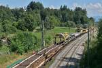 Blick auf die Schwellentransportwagen mit zwei Portalkränen und den Gleisumbauzug MATISA P 95 der SCHWEERBAU am Ende. Höhenreute, 09.07.2023