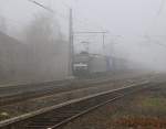 Schwarze Loks im Nebel: 185 563-4 mit Containerzug in Fahrtrichtung Süden. Aufgenommen am BÜ Eltmannshausen/Oberhone am 26.03.2014.