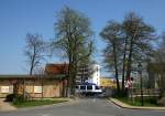 Ein HEX-Triebwagen nach Halle fhrt aus dem Bahnhof Ilsenburg aus und berqueert dabei die Schmiedestrae, welche als Zufahrt zum im Hintergrund zu sehenden Ilsenburger Radsatzwerk dient.