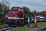  In Putbus stehende Lok 114 703 mit beladenen Schmalspurtransportwagen, auf denen Schmalspurwagen und die Lok 99 783 stehen.