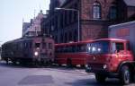 Helsingør: HHGB (Helsingør-Hornbæk-Gilleleje-Banen) am 5. Juli 1973: Die Diesellok M4 (Scandia 1933, ex-HHJ M4) hält mit einem Güterwagen mitten auf der Strasse (Jernbanevej) auf dem Verbindungsgleis zwischen der HHGB und dem DSB-Bahnhof Helsingør. Ein DSB-LKW sperrt für die Weiterfahrt.  