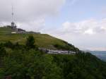 Gipfelstürmer: Beh2/6 3 und 4 haben die Bergstation am Gipfel des Puy de Dôme gleich erreicht. Im Hintergrund liegt Clermont-Ferrand.


Seit Mai 2012 fährt die neuerbaute Zahnradbahn Panoramique des Dômes zum Gipfel des Puy de Dôme. Die 5,3 Kilometer lange Strecke führt von der Talstation (Maison de Site) zur Gipfelstation (Gare de Sommet) auf 1406 Meter Höhe. Die meterspurige Strecke hat Y-Stahlschwellen und eine Zahnstange nach System Strub. Die vier Triebwagen Beh 2/6 (Typ GTW) wurden von der Firma Stadler in der Schweiz gebaut. Der 1465 Meter hohe Puy de Dôme ist ein Vulkangipfel, der die zu seinem Fuße liegende Großstadt Clermont-Ferrand um gut 1000 Meter überragt. 

2014-07-26 Puy de Dôme 