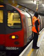 Unterstützung in der Rush Hour: Hilfskraft mit Signalkelle in der Station  Swiss Cottage .