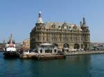istanbul-haydarpascha Der Kopfbahnhof Haydarpascha (Haydarpaşa) ist Endpunkt der Eisenbahnen aus Anatolien und liegt direkt am Bosporus auf der asiatischen Seite Istanbuls. Die Verbindung zur europ�ischen Seite Istanbuls erfolgt mit den Bosporusf�hren. Nach Fertigstellung des Marmaray-Projekts (Bahn-Untertunnelung des Bosporus) wird er seine zentrale Rolle aber verlieren. 
Nach den bisherigen Planungen (wogegen es aber auch Widerstand gibt) werden dann hier keine Personenz�ge mehr verkehren.


Der Bahnhof wurde von 1906-1908 nach Pl�nen der deutschen Architekten Otto Ritter und Helmuth Conu von der Firma Philipp Holzmann gebaut. Den Namen erhielt er zu Ehren eines ber�hmten Paschas, der unter Selim III. dem Hof diente.

11.04.09


