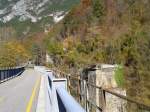 Blick auf die neue und die Reste der alten Ponte di Dogna. Die Ponte di Dogna ist die einzige moderne Stahlbetonbrücke der alten Pontebbana, heute dient sie aber auch nur mehr dem Ciclovia Alpe Adria Radweg. Die alte Brücke rechts war eine Stahlfachwerkbrücke. Diese fiel 1969 jedoch dem Hochwasser zum Opfer. Bis zu jener Zeit, als die italienische Staatsbahnen eine Behelfsbrücke aufbauten, fuhren ÖBB-2043er bis auf italienisches Hoheitsgebiet. Im Gegenzug wurden mehrere FS-Lokomotiven der Reihe E 626 über Villach und Tauern zum Brenner überführt. Aufgenommen am 8.11.2015