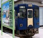 Akita Nairiku-Bahn, Nordabschnitt: An der nrdlichen Endstation Takanosu steht Wagen 8805 vor einer grossen Werbetafel fr die touristischen Attraktionen der Gegend, allen voran die Trommelfeste mit