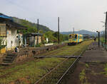 Die Heisei Chikuhô Bahn im Nordosten der Insel Kyûshû: Kreuzung mit Triebwagen 406 in Sakiyama. Eine typische Szene auf dem Land, wo die älteren Dorfbewohner sich um ihre Bahnhöfe kümmern, indem sie den Bahnsteig von Unkraut befreien, wie vorne links zu sehen ist. 16.April 2023 