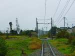 Takaoka Manyô-Linie, neue Wagen Serie 1000: Durchs Hafengebiet mit Sicht auf die Hafenkräne.