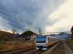 Tokyo S-Bahn, Serie 233: S-Bahnzüge aus Tokyo fahren immer weiter aufs Land hinaus und ins Gebirge hinein, je weiter sich die Agglomeration früher fast unbewohnter Gebiete bemächtigt. Hier durchfährt der Zug mit Steuerwagen KUHA 233-51 das Dorf Torisawa, bereits hoch im Gebirge westlich von Tokyo. 10.März 2013. 